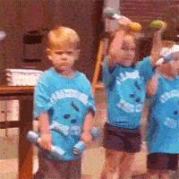 Video gif. We see three children in matching blue t-shirts holding tiny barbells. Two of them hold up the barbells energetically, while the third makes no effort to lift them from his sides. As we zoom in on him, he coldly stares back at us.