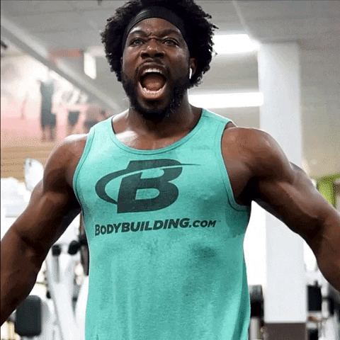 Video gif. A muscular man yells out like a warrior as he flexes his bulging arm muscles. 