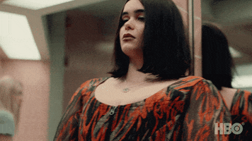 TV gif. Barbie Ferreira as Kat in Euphoria. She leans against a mirrored wall and angstily looks over her shoulder.