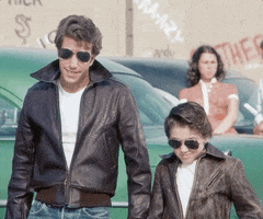 TV gif. Henry Winkler as The Fonz wears his signature pompadour, leather bomber jacket and aviators, standing next to a young kid also wearing a pompadour, leather bomber jacket and aviators. They both give us a thumbs up.