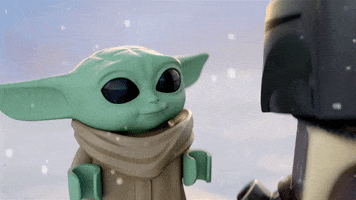Star Wars gif. Baby Yoda rendered like a LEGO bouncing excitedly as light snow falls.