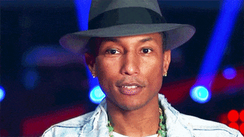 TV gif. Pharrell Williams on The Voice cocks his head to the side and winks at us.