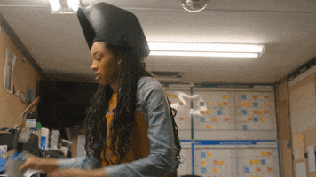 TV gif. Troy Leigh-Ann Johnson as Kendra in On My Block picks up a hand torch and pulls a welding helmet over her face.