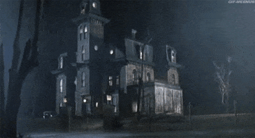 Movie gif. Dark, eerie nighttime view of the Addams Family house, which lights up with lightning flashes while rain pours down.