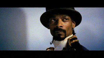 Music video gif. Snoop Dog in Welcome to the World of Plastic Beach, wearing a black top hat and regency naval attire nods seriously looking off into the distance. 