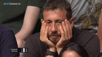 Sports gif. Tennis spectator rests his hands on his face and gazes forlornly at the match, appearing weary and defeated.