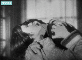 Movie gif. Louise Brooks as Lulu in "Pandora's Box" cranes her head back with her arms around Francis Lederer as Alwa's shoulders as he kisses her neck and face.