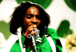 Music video gif. André 3000 in the Outkast video for Hey Ya holds onto a microphone and jerks from side to side as he sings into it. Text, "Alright, alright, alright, alright, alright." 