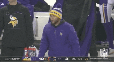 Sports gif. A Minnesota Vikings coach power-fives an incoming player, shouting "great job!"