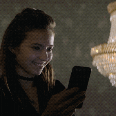 TV gif. Anjelica Bette Fellini as Blair in Teenage Bounty Hunters. She's grinning down at her phone and she types, "You're mad sexy."
