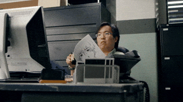 TV gif. SungWon Cho as Joe Furuya in Anime Crimes Division sits at a desk looking at a document, then notices something on the computer screen and waves his colleague over to look at it.