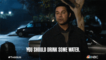 TV gif. Jon Huetras as Miguel Rivas on This Is Us looks over at some with a disappointed look on his face as she stands outside at night. He says, “You should drink some water.”