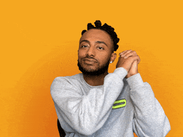 Celebrity gif. Smiling, rapper Amine clasps his hands and holds them on each side of his head, then gives two thumbs up.