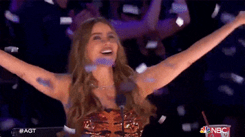 Reality TV gif. Sofia Vergara on America's Got Talent smiling and raising her arms in celebration as confetti rains down.