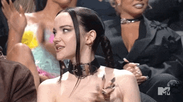 Celebrity gif. Dove Cameron claps with cheerful energy as she nods her head in agreement.