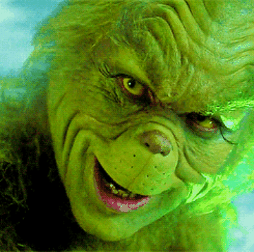 Movie gif. Closeup of Jim Carrey as the Grinch with an eerie smile spreading slowly across his face.