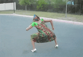Video gif. Woman in a dress and headwrap and wearing white heels dances earnestly, pumping her arms up and down as she squats down.