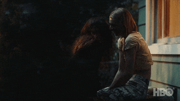 TV gif. Zendaya as Rue and Hunter Shafer as Jules on Euphoria are outside someone's house. Jules sits on something and Rue leans toward to make out with her.