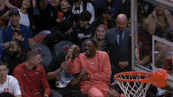 Sports gif. Bam Adebayo and RJ Hampton of the Miami Heat are sitting on the bench and they're cracking up laughing. They hold on to each other busting up as they stomp their feet.