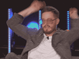 Celebrity gif. Olivier Primeau, wearing a jean jacket and clear glasses, excitedly uses both hands to point toward someone as if to say, "Yes!"