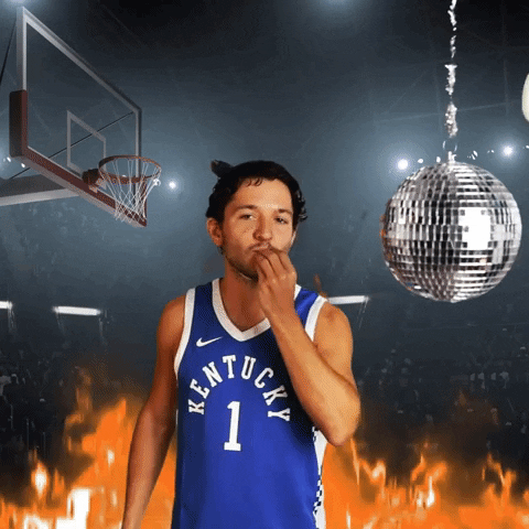 Video gif. Person wearing a Kentucky Wildcats jersey does a chef's kiss in front of an edited background showing a basketball stadium, disco ball, and flames. Text flies by, "Off the glass!'
