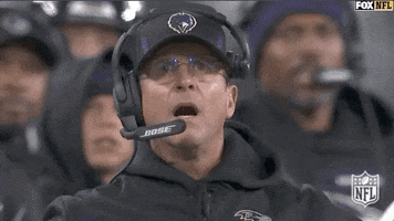 Sports gif. John Harbaugh, head coach of the Baltimore Ravens, is stunned by the play, putting both hands on his head and his jaw dropping in horror.