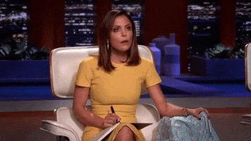 Reality TV gif. Bethenny Frankel on Shark Tank. She's sitting cross legged and she looks astonished and what she's seeing.