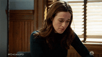 TV gif. Marina Squerciati as Burgess on Chicago PD looks over with worry on her face before resting her forehead on her palm. 