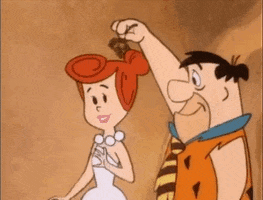 Cartoon gif, Holiday gif. Fred Flintstone holds a sprig of mistletoe over the head of his wife Wilma, who smiles as he kisses her on the cheek.