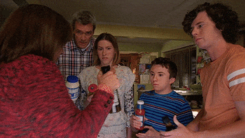 TV gif. The Heck family from The Middle stand in a circle. They each hold a different condiment container in their hands as they toast with confused looks on their faces.