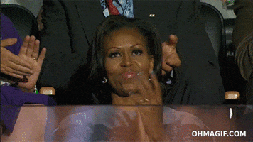 Politics gif. Michelle Obama, claps from her seat in an audience.
