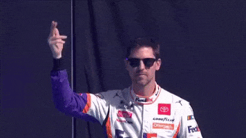 Sports gif. NASCAR driver Denny Hamlin motions for the crowd to cheer then holds a hand up to his ear.