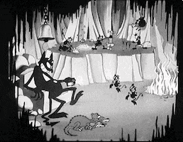 Disney gif. A vintage black and white cartoon of hell from Hell's Bells. The devil sits on a throne and taps his foot as little demons dance in front of him. A three headed dog sleeps at his feet and there’s a demon band playing several instruments while flames erupt in the corner. 