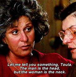 Movie gif. Lainie Kazan as Maria in My Big Fat Greek Wedding points a knowing finger and says to Nia Vardalos as Toula, “Let me tell you something, Toula. The man is the head, but the woman is the neck.”