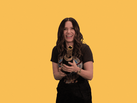 Pohyblivý gif se smějící se ženou, držící láhev šampaňského z které vystřelují konfety.