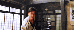 Movie gif. Keanu Reeves as Neo in The Matrix. He's in a dojo wearing a karate uniform and has his fists up.