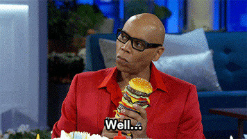 Celebrity gif. TV personality RuPaul holds a tall toy cheeseburger and says "well..." while curling his mouth into a sardonic smile. Text, "Well..."