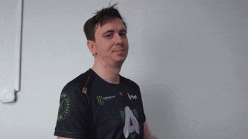 Video gif. Man in a black gamer jersey presses his palms together as a prayer and looks wistfully up at the sky.