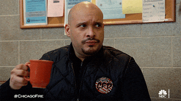 TV gif. Joe Minoso as Joe Cruz looks over at someone with concern and then lifts an eyebrow up as he takes a sip out of his mug.