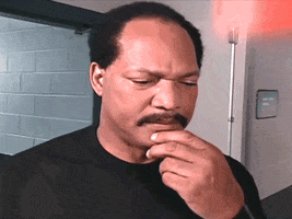 Sports gif. Ron Simmons, a WCW World Heavyweight Champion, rubs his chin and ponders. He makes a decision and looks around before saying, "DAMN!"