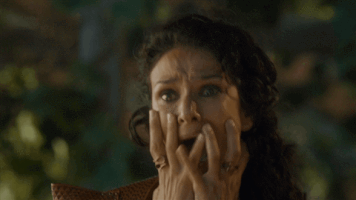 TV gif. Indira Varma as Ellaria on Game of Thrones shrieks, wide-eyed, with horror, her hands crawling down the sides of her face and trembling.