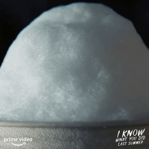 Ad gif. Dark reddish-brown syrup pours onto a cup of shaved ice, slowly sinking into it. In the corner is the logo for the Prime Video show, “I know what you did last summer.”