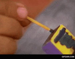 Video gif. Close up of person lighting match, the fire bursting then shrinking into a small flame.