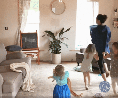 Working mom with a laptop being trailed by her three young children.