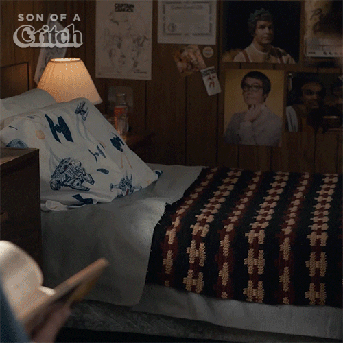 TV gif. Benjamin Evan Ainsworth as Mark on Son of a Critch, flops face first onto his bed and pillow with his day clothes on. 