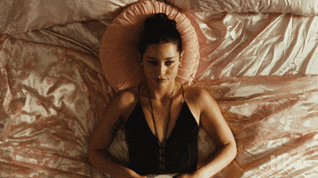 TV gif. Alexa Demie as Maddie on Euphoria lays on her pink bed very still as she thinks.