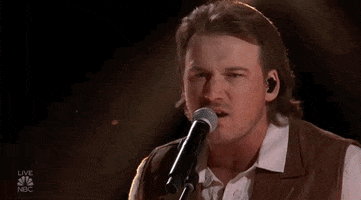 Celebrity gif. Morgan Wallen performing at the 2022 Billboard Music Awards raises up his hands pressed together in prayer.