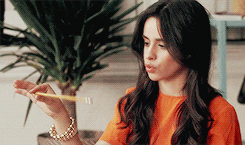 Celebrity gif. Camila Cabello holds a pencil out in front of her and waves it around to make it look like it’s jiggling. She purses her lips out and has a vacant, bored expression on her face. 