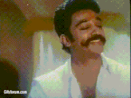 Video gif. A grainy clip shows a man with a handlebar mustache smiling as he holds his hands in prayer and looks upward.
