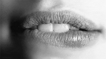 Video gif. In a sexy manner, a woman bites her lip. 
